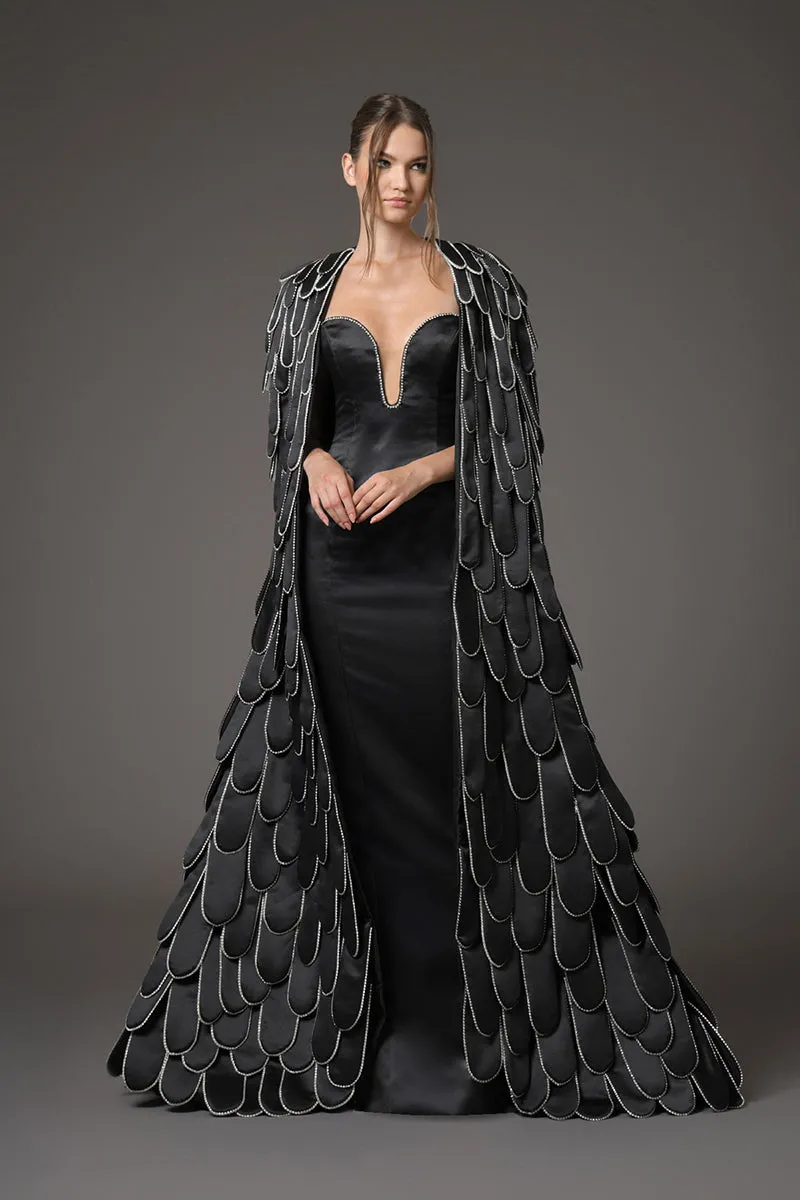 Black silk scuba dress featuring a cape with an overflow of layered 3D hand-crafted plumes in scuba and crystals