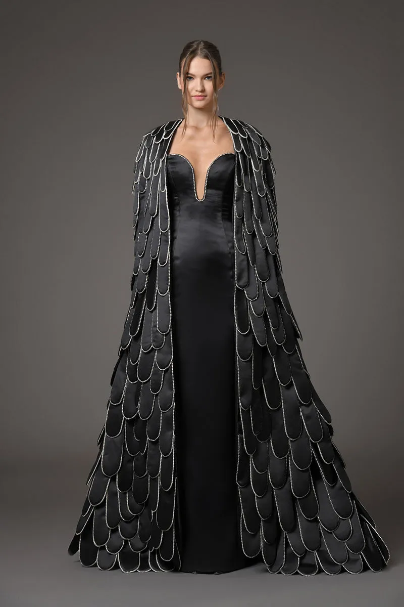 Black silk scuba dress featuring a cape with an overflow of layered 3D hand-crafted plumes in scuba and crystals
