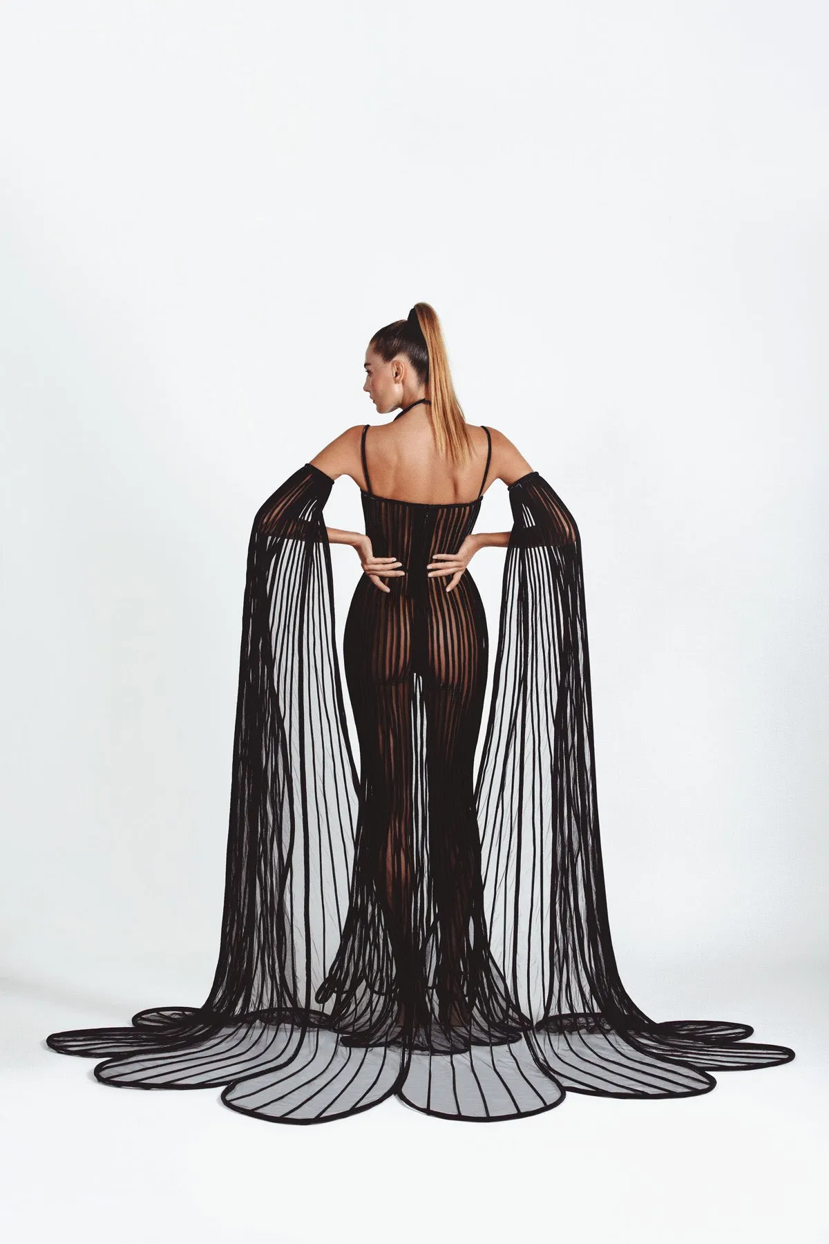 Sheer mermaid signature dress in black latex and tulle worn with cape sleeves handcrafted in 3D tubes